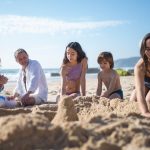 Family builds sandcastles while enjoying a sunny day at a beach in Portugal.